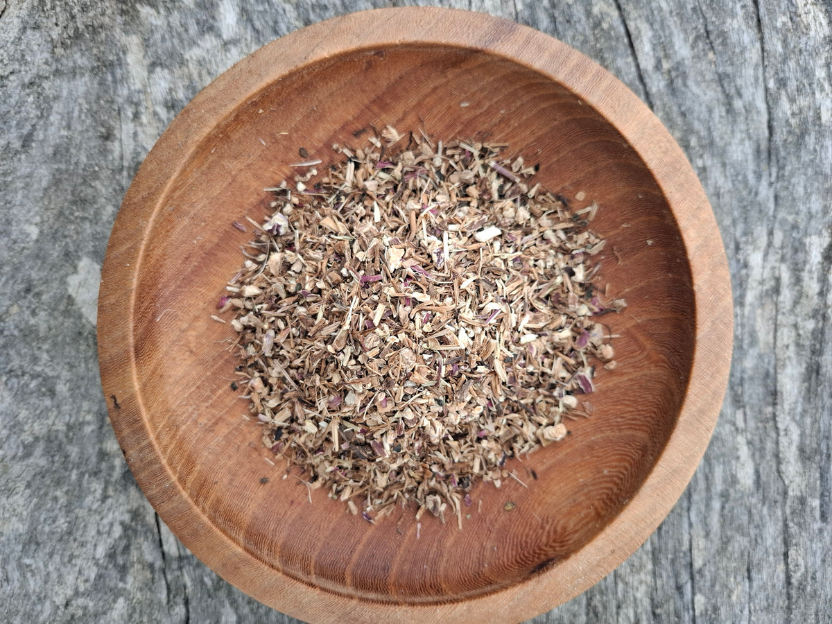 Wooden bowl with dried herbs on a textured surface