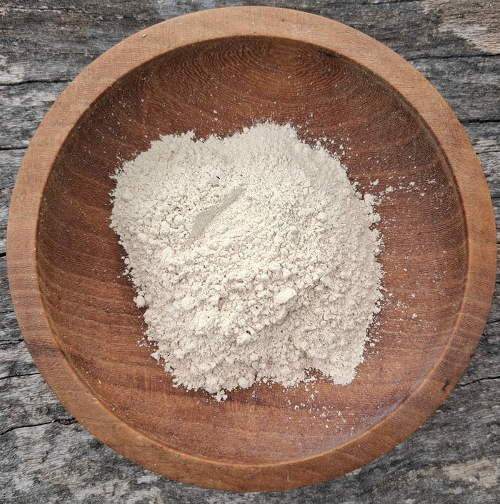 dried clay in a wooden bowl on a rustic bench top