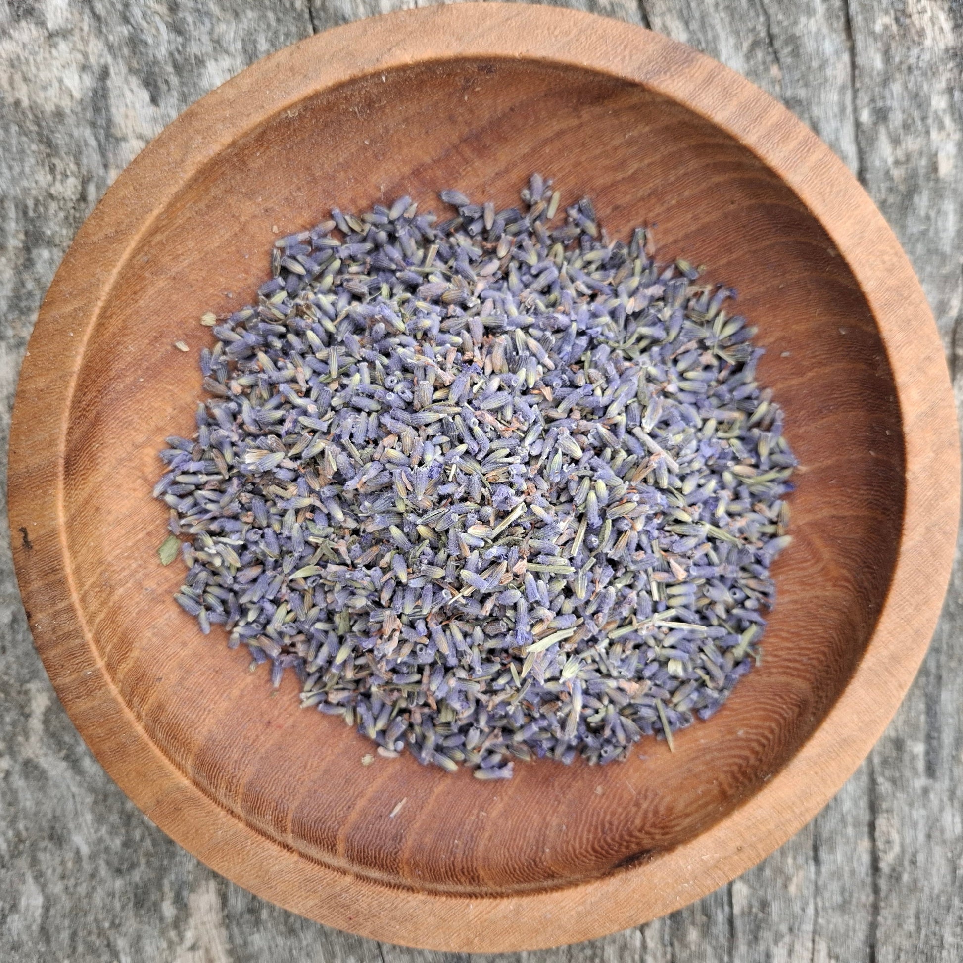 Dried lavender flowers in a wooden bowl on a rustic wooden surface