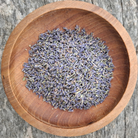 Dried lavender flowers in a wooden bowl on a rustic wooden surface