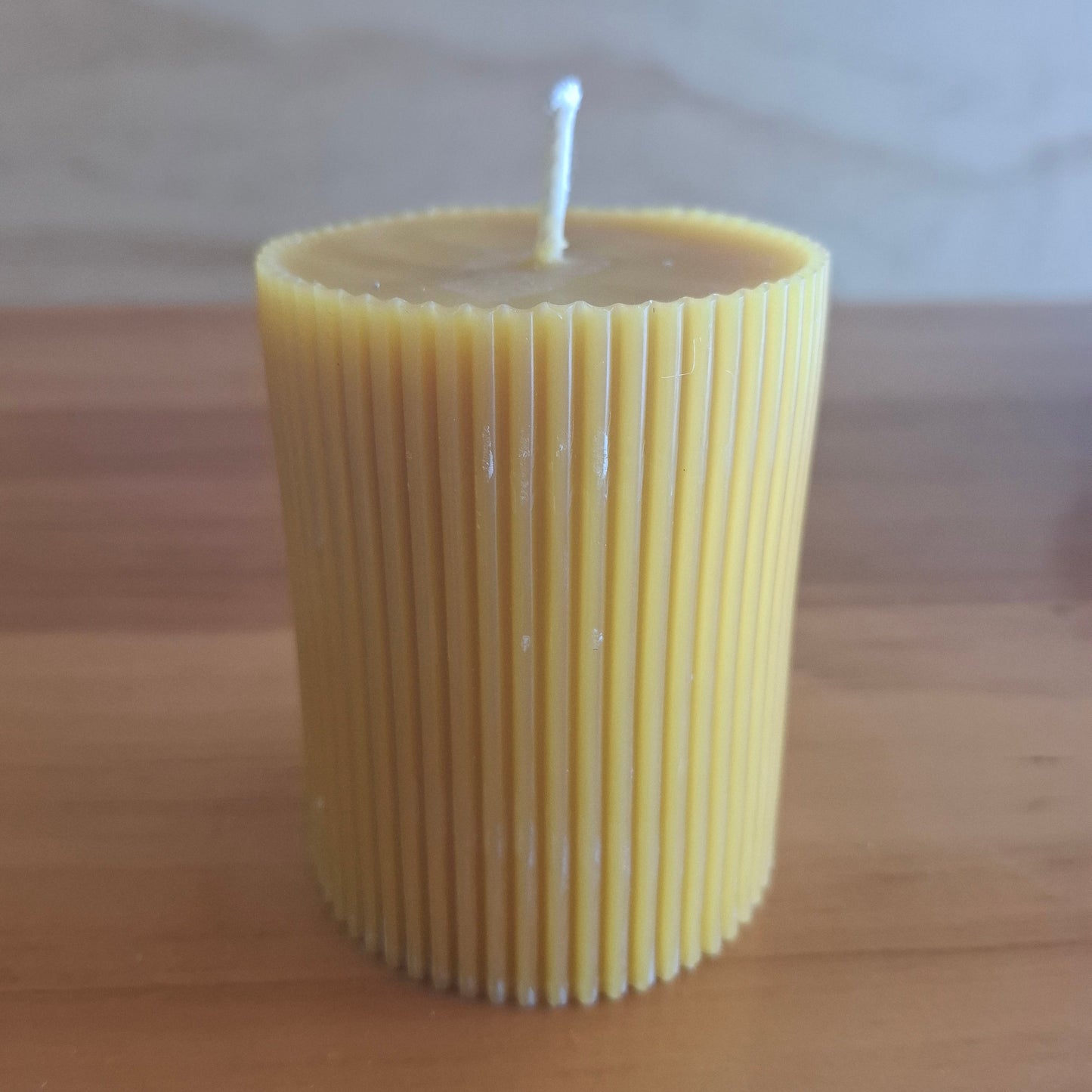 beeswax candle handpoured with organic cotton wick set on wood table