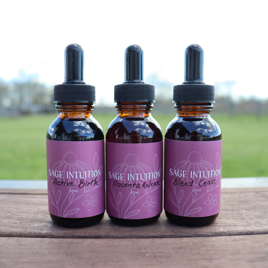 Three bottles of Sage Intuition tinctures on a wooden surface with a blurred natural background