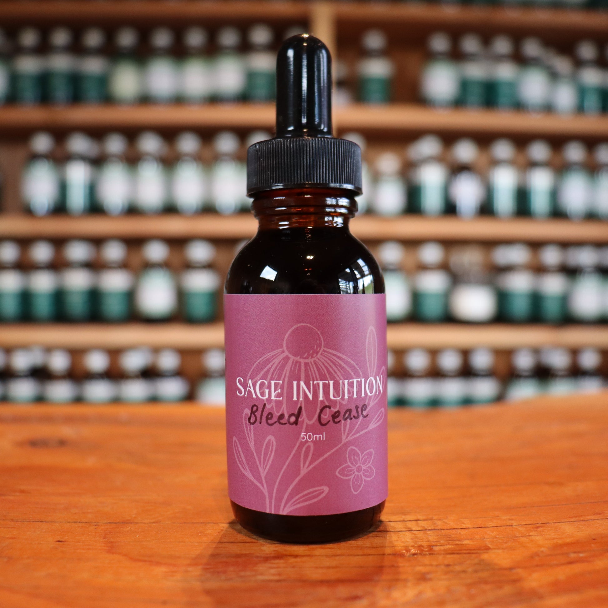 Bottle of 'Sage Intuition' bleed cease after birth tincture on a wooden surface with shelves in the background.