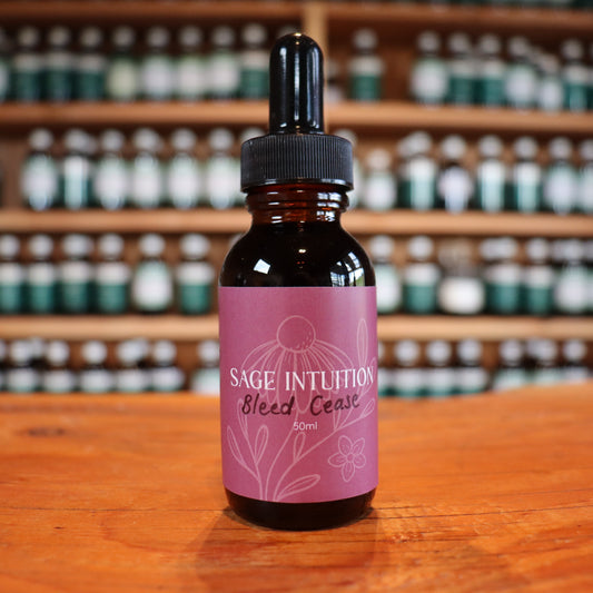 Bottle of 'Sage Intuition' bleed cease after birth tincture on a wooden surface with shelves in the background.