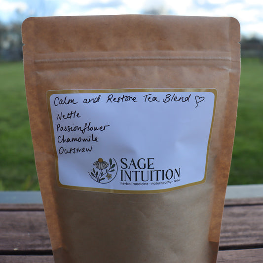 Tea blend package with 'Sage Intuition' label on a wooden surface with grass and sky in the background