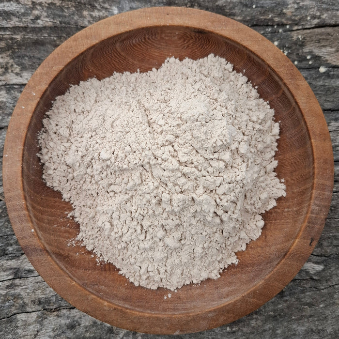 Wooden bowl filled with white flour on a rustic wooden surface