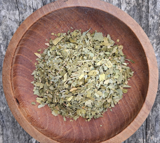 Dried herbs in a wooden bowl on a rustic wooden surface