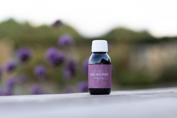 Sage Intuition Immune Boost herbal tincture bottle with a purple label and white cap, pictured outdoors.