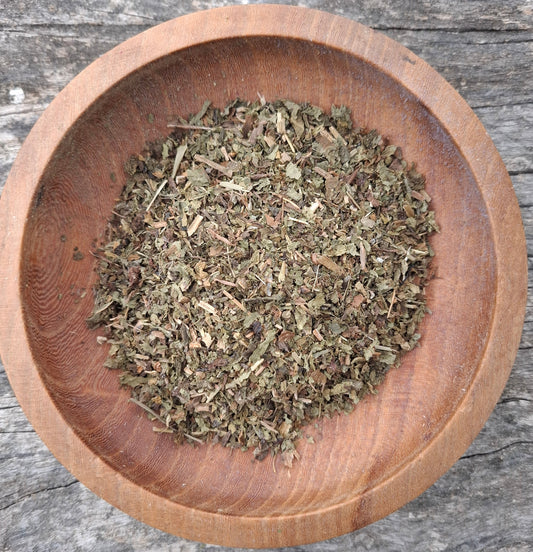 Wooden bowl filled with dried herbs on a wooden surface