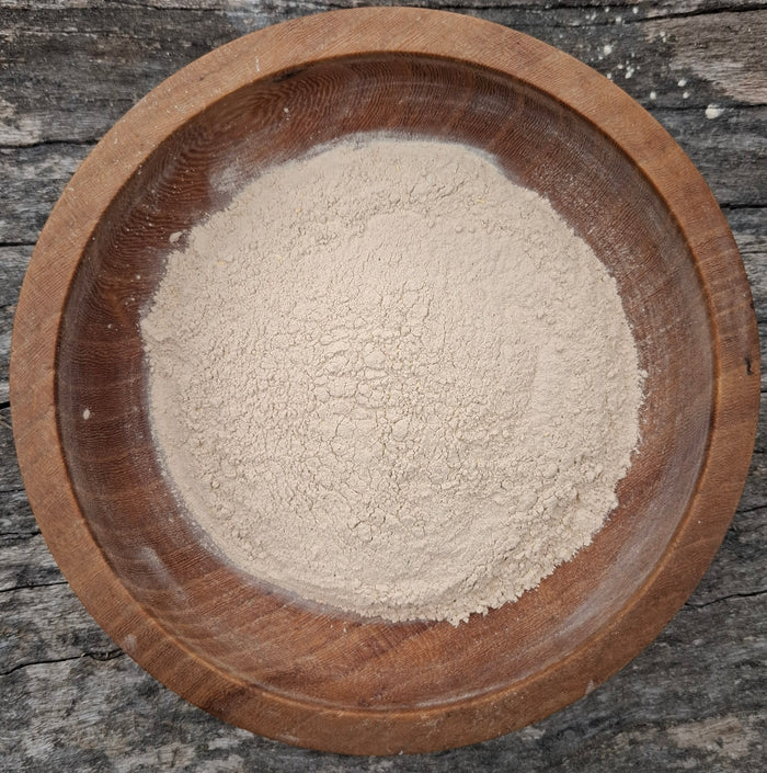 Wooden bowl filled with flour on a rustic wooden surface