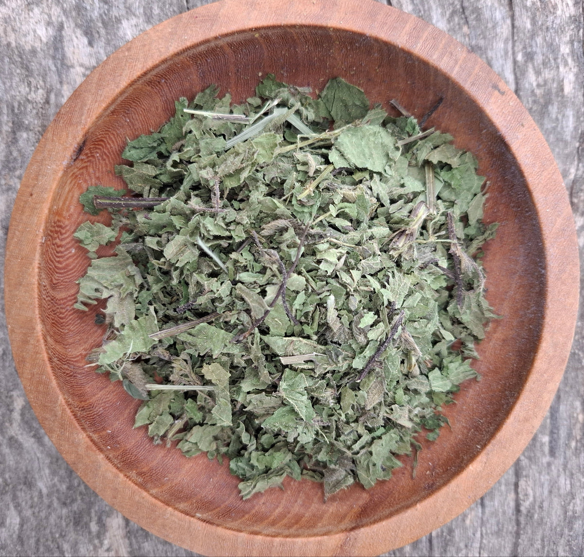 Dried herbs in a wooden bowl on a rustic wooden surface