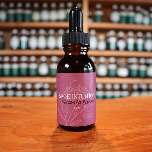 Bottle of Sage Intuition placenta release tincture on a wooden surface with shelves of similar bottles in the background.